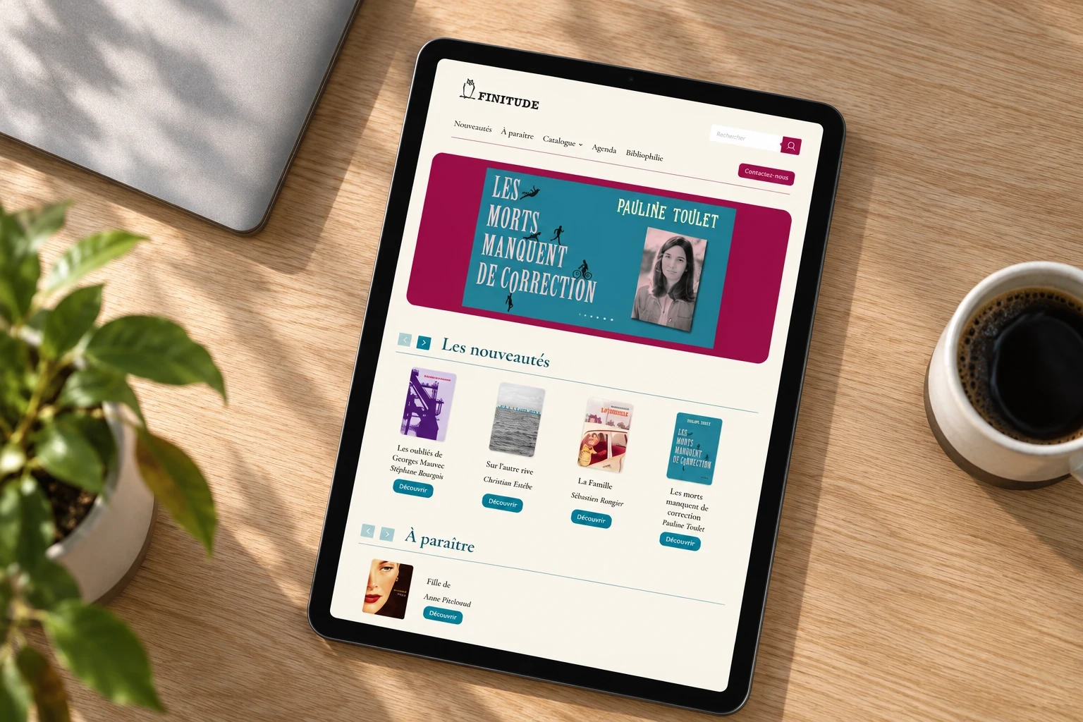 Site des Éditions Finitude sur un iPad vu du dessus, posé sur un bureau en bois.