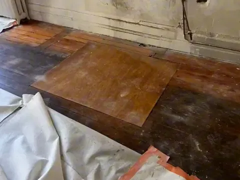 Plancher en pitchpin recouvert d’un panneau, photographié avant réparation.
