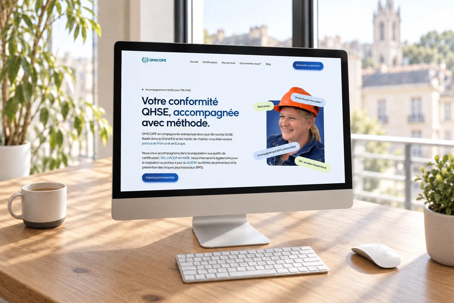 Site QHSCOPE affiché sur un écran de Mac, avec clavier et souris sur le bureau.